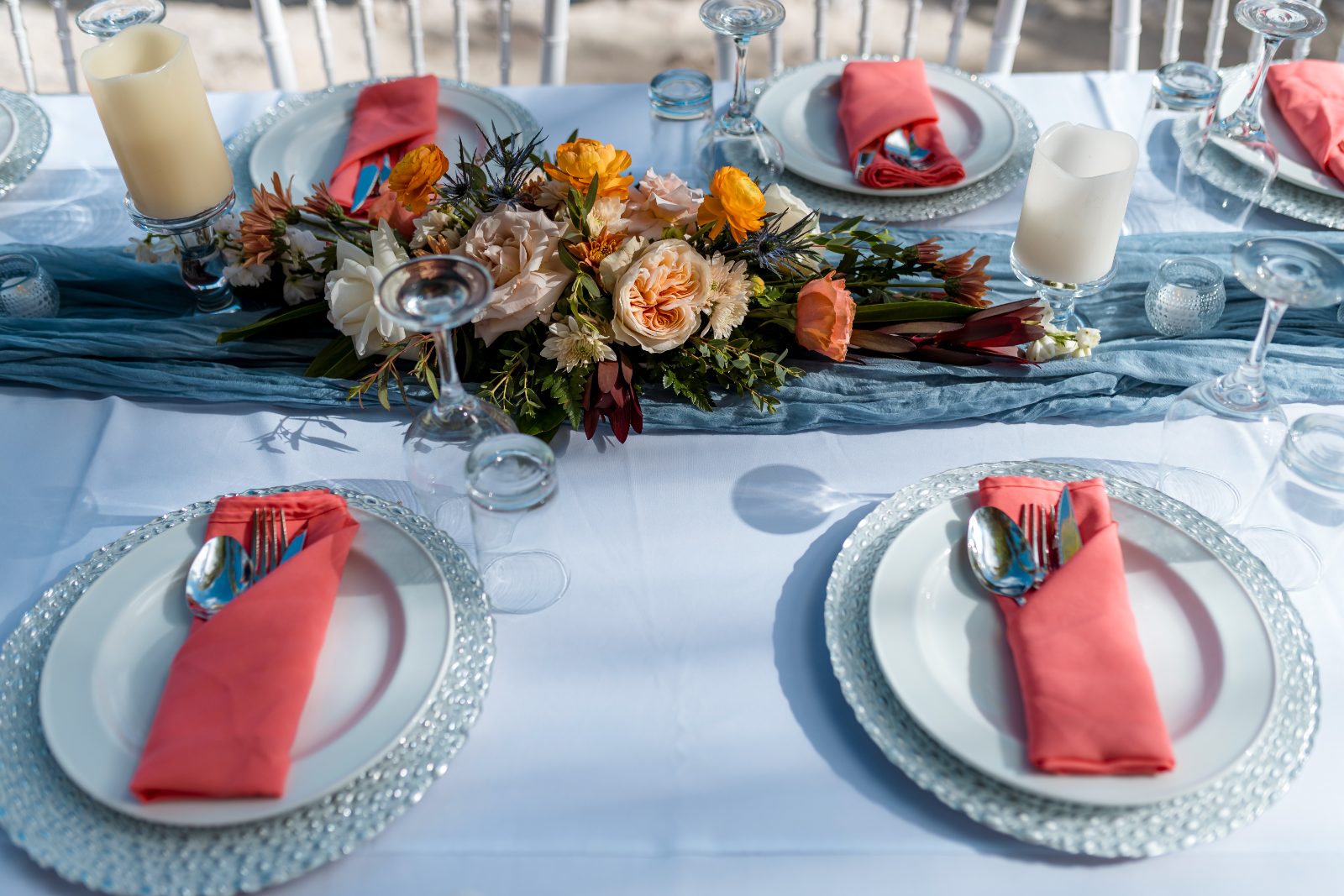 The wedding table at Avila Beach Hotel features elegant place settings, coral napkins, and a floral centerpiece