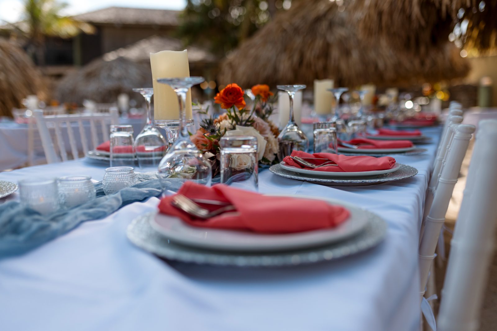 The table is set for a wedding reception outdoors at Avila Beach Hotel, featuring pink napkins, candles, and floral centerpieces