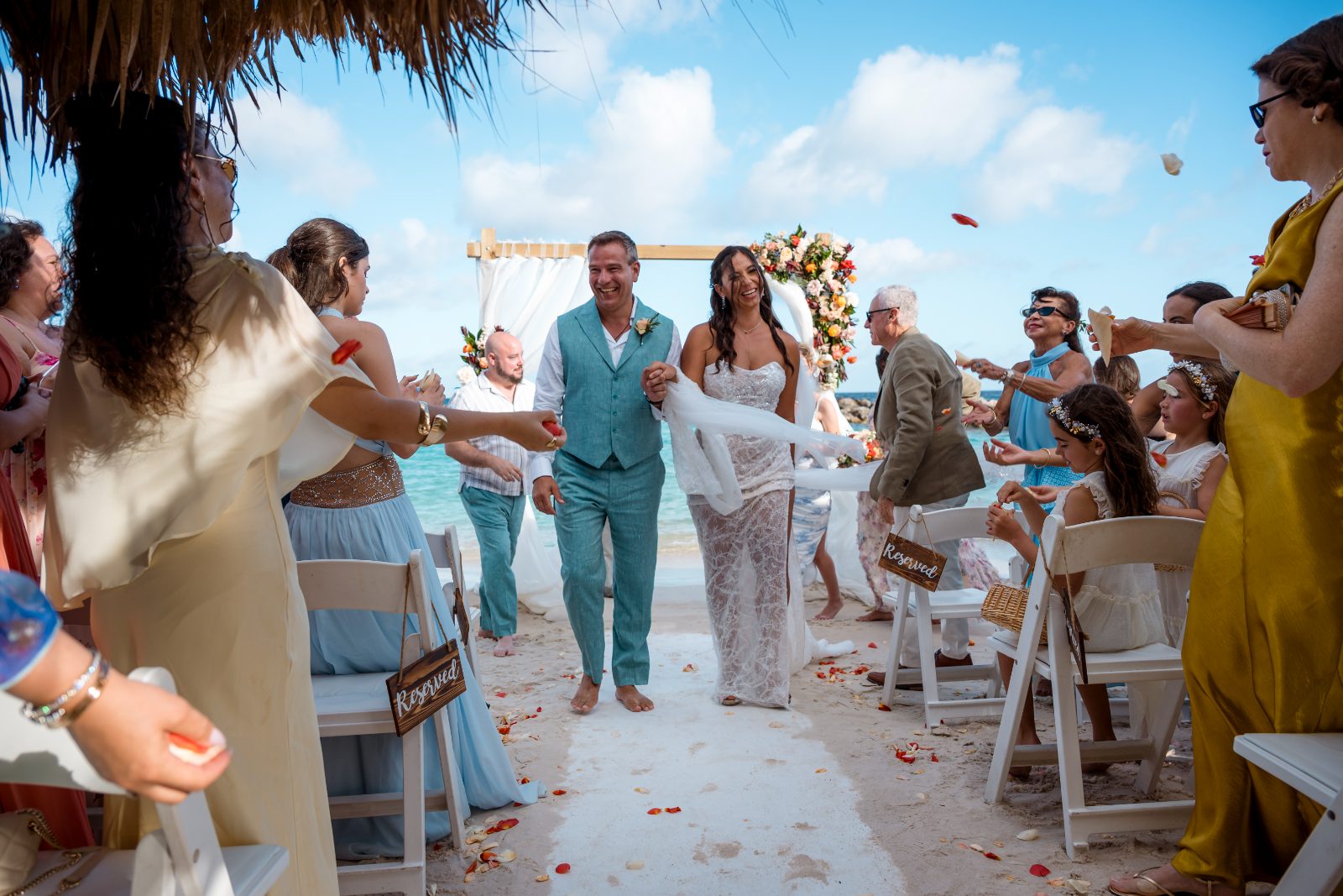 Anika and Sarne walk down the aisle at Avila Beach Hotel, surrounded by guests throwing rose petals