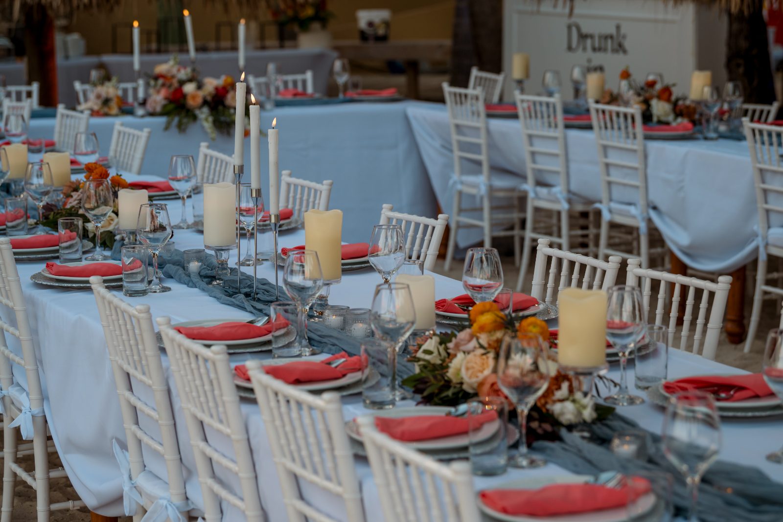 The wedding setting features elegantly arranged tables with white chairs, candles, and floral centerpieces, all at Avila Beach Hotel