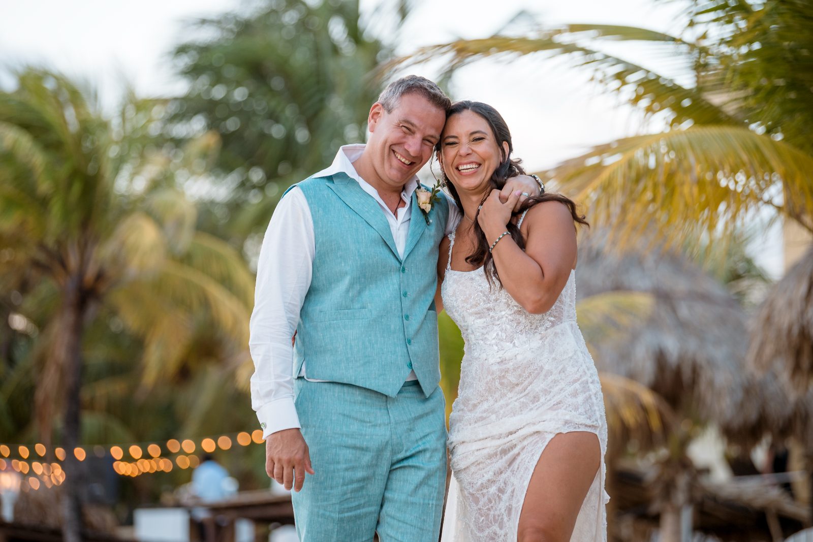 Anika and Sarne smile together outdoors at Avila Beach Hotel, surrounded by palm trees and soft evening lights after their wedding ceremony