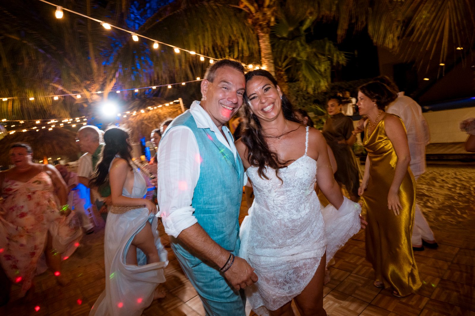 Anika and Sarne dance at their wedding reception at Avila Beach Hotel, surrounded by guests and decorated with string lights