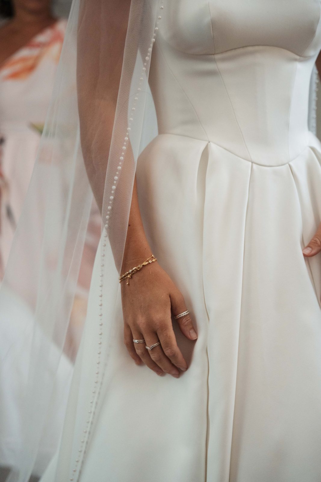 Cailey, wearing a wedding dress and veil, is holding hands with Noel at their wedding ceremony at Avila Beach Hotel in Curaçao