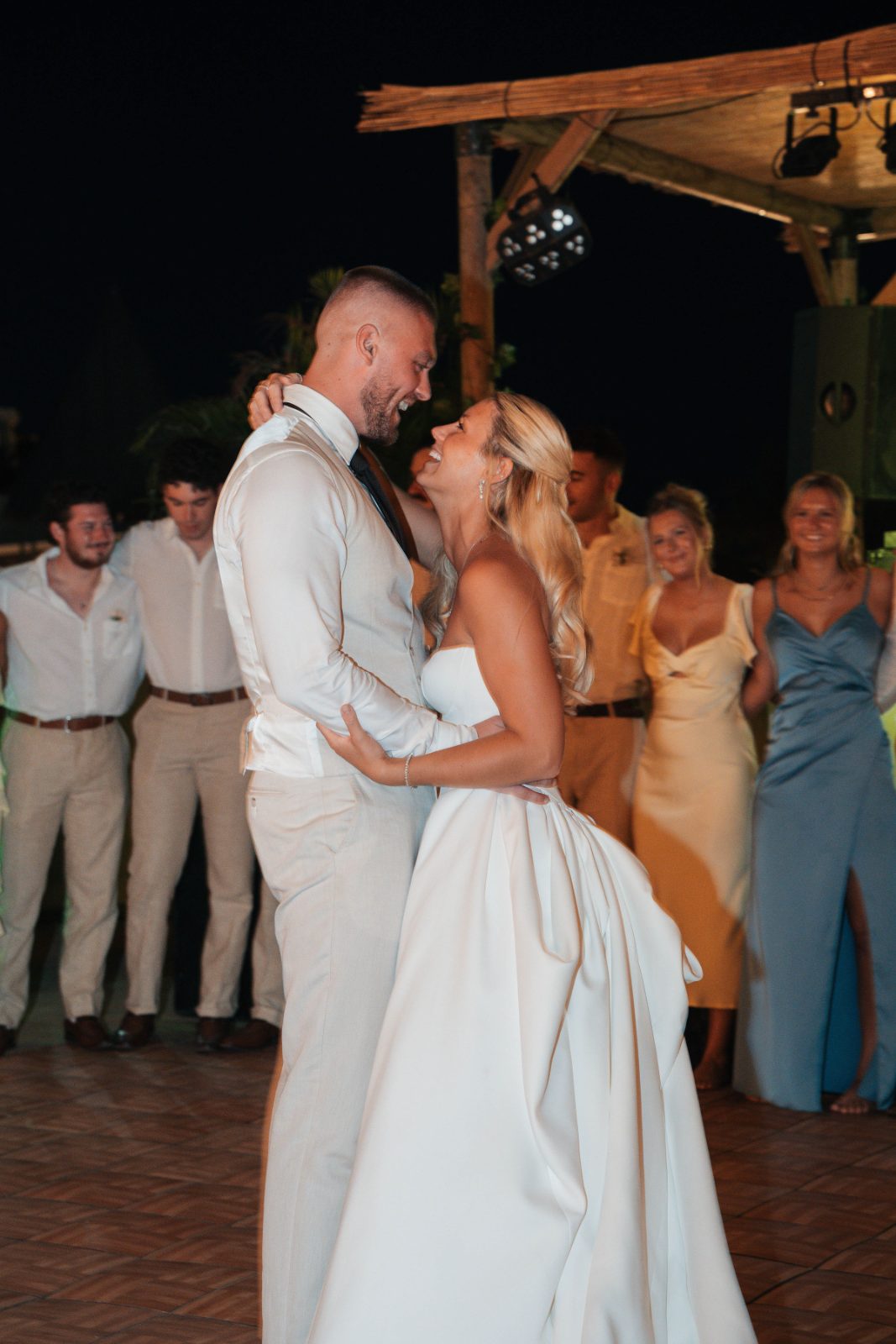 Cailey and Noel are dancing together at their wedding reception at Avila Beach Hotel in Curaçao, surrounded by guests in casual attire