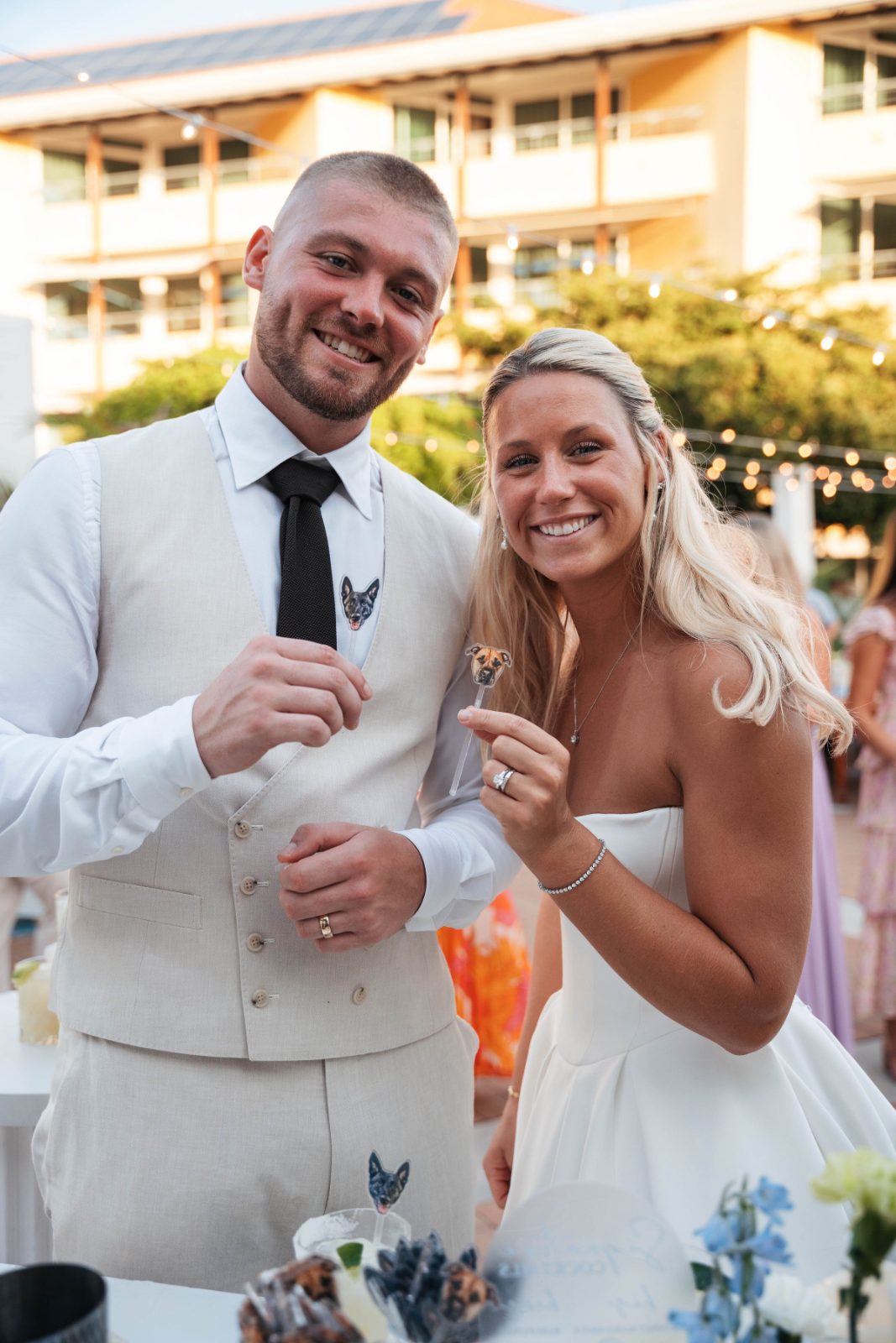 Cailey and Noel are smiling and holding wedding favors at their reception outside the Avila Beach Hotel in Curaçao