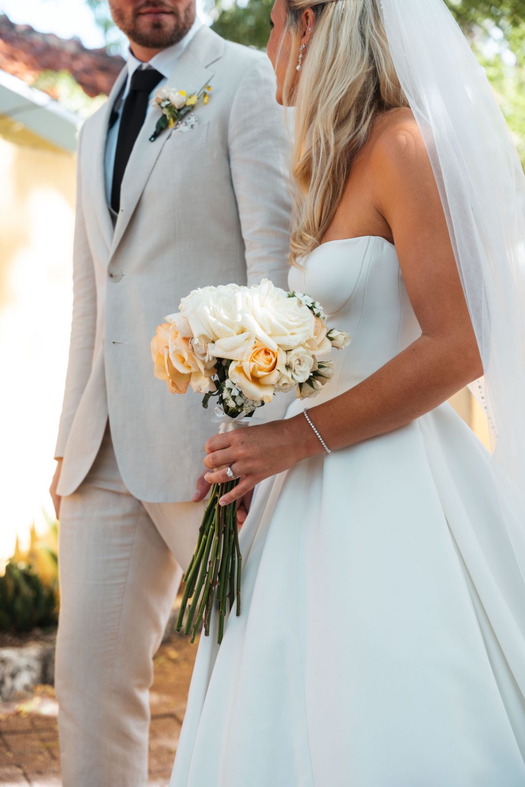 Cailey and Noel are walking together at their wedding at Avila Beach Hotel in Curaçao, with Cailey holding a bouquet of flowers