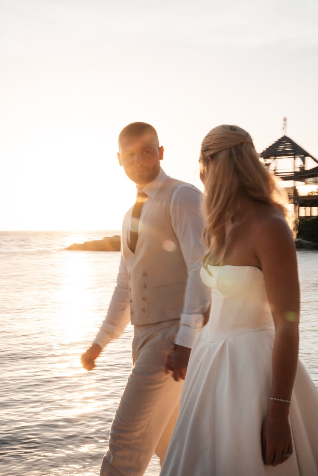 Cailey and Noel walk hand in hand by the water at the Avila Beach Hotel in Curaçao during sunset