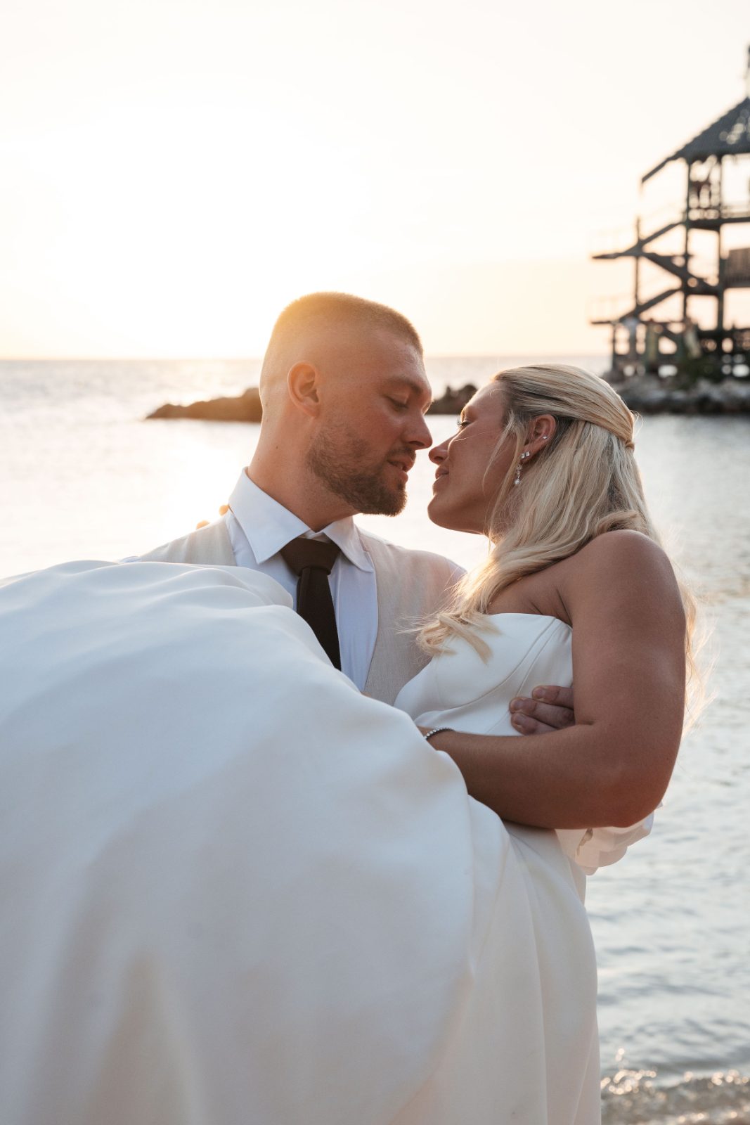Cailey and Noel are embracing at sunset by the beach at Avila Beach Hotel in Curaçao
