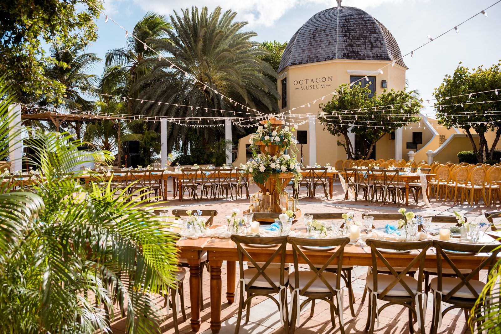 Cailey and Noel’s wedding reception is set at Avila Beach Hotel in Curaçao, featuring a decorated outdoor space with tables and floral arrangements