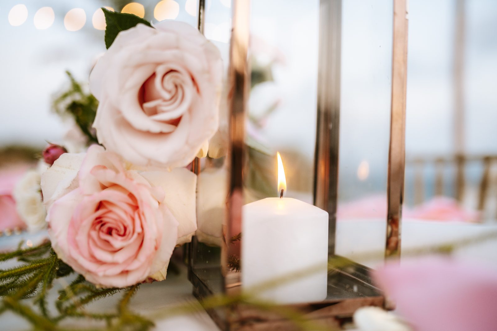 Christine and Jesse's wedding is set at a private villa in Curaçao, featuring pink roses and a lit candle on a table