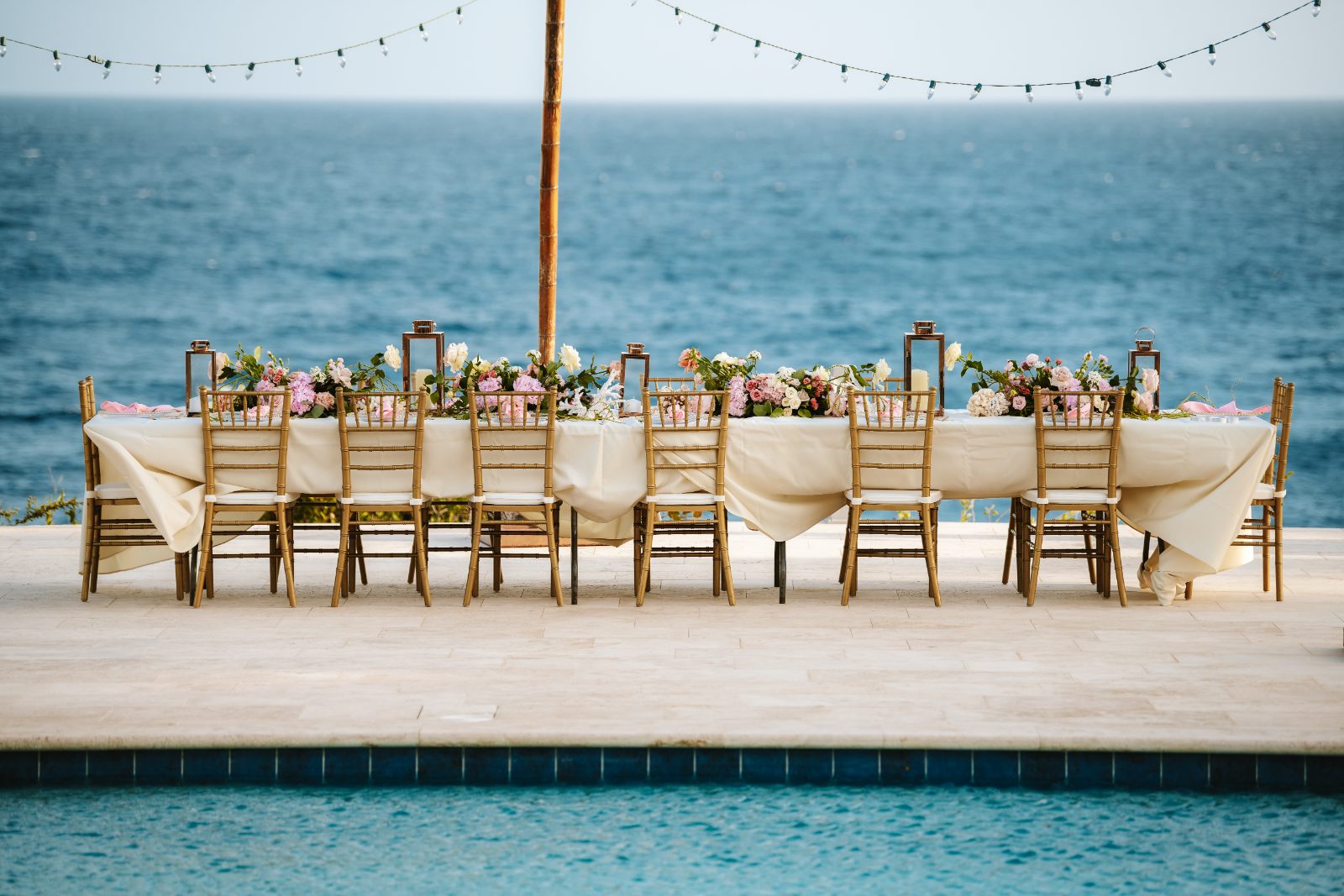 Christine and Jesse's wedding reception table, decorated with flowers, is set by the ocean at a private villa in Curaçao