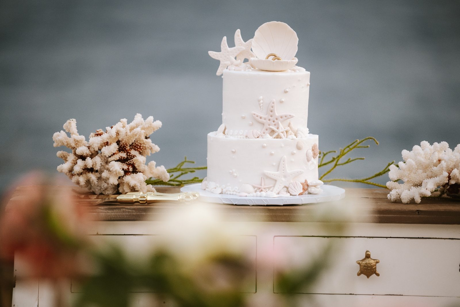 Christine and Jesse's wedding cake, decorated with seashells and starfish, is displayed on a table at a private villa in Curaçao