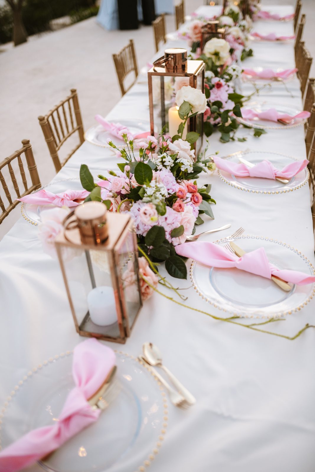 Christine and Jesse's wedding reception features a long table set at a private villa in Curaçao, decorated with flowers, candles, and pink napkins