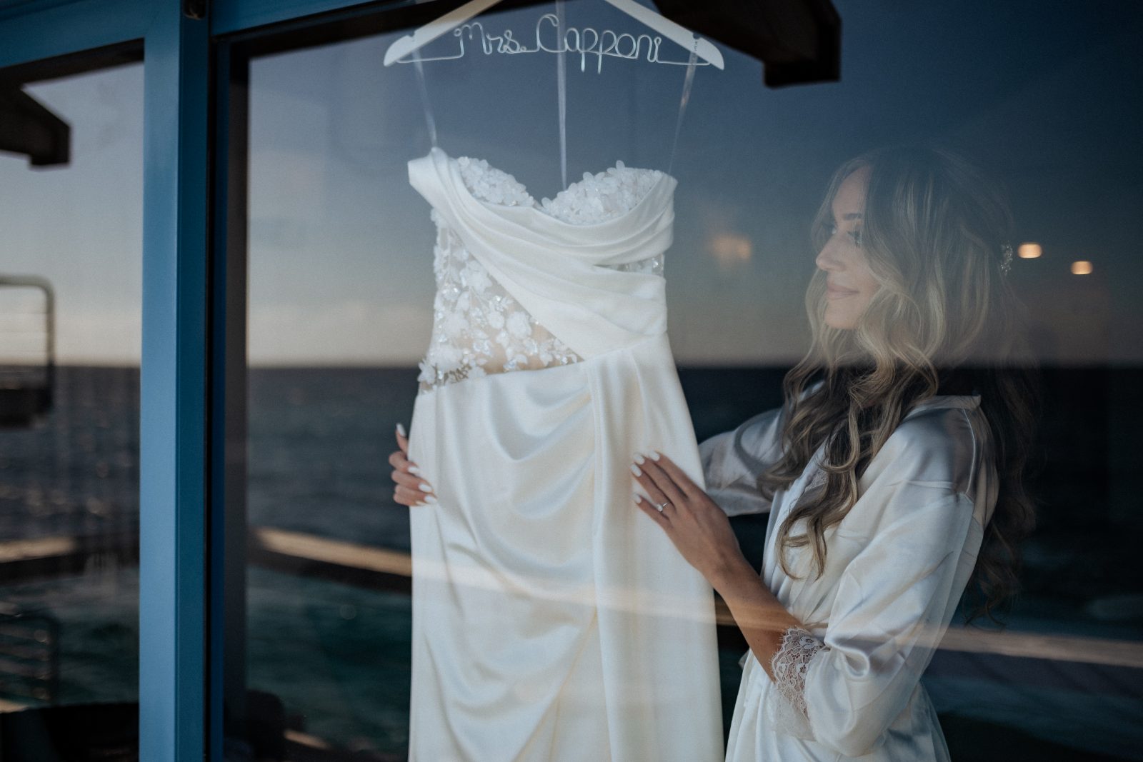 Erica holds her wedding dress in front of a window at the Avila Beach Hotel in Curaçao