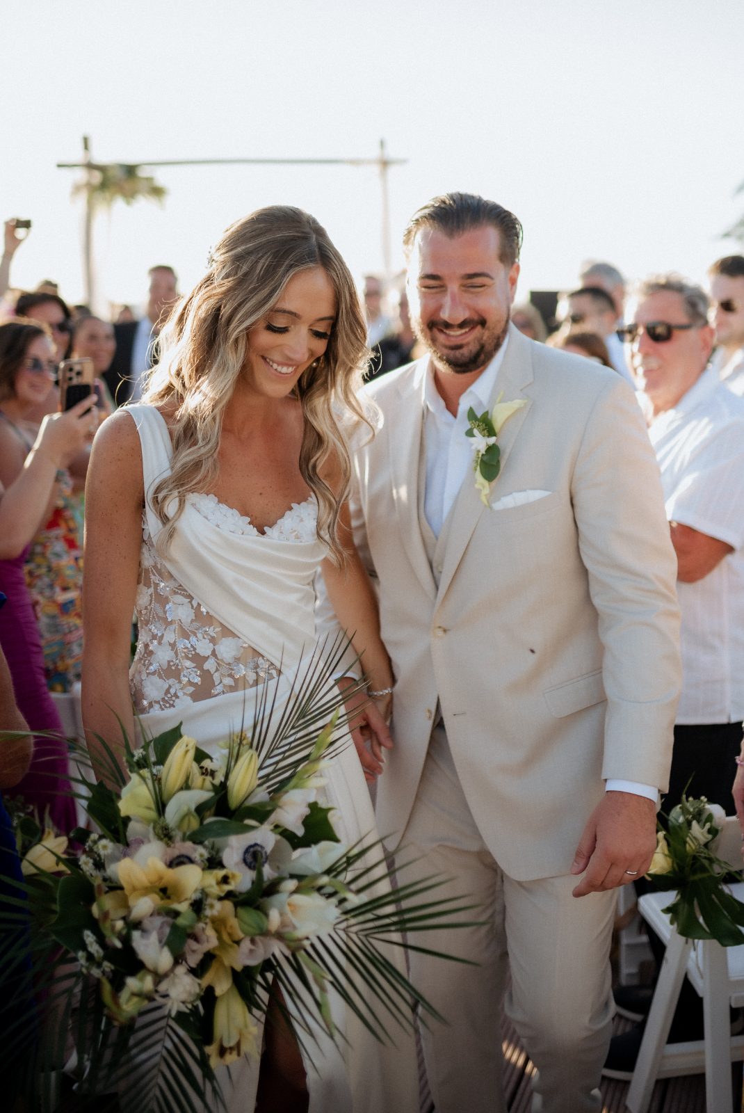 Erica and Derek walk together, hand in hand, during their wedding ceremony at Avila Beach Hotel in Curaçao, with guests in attendance