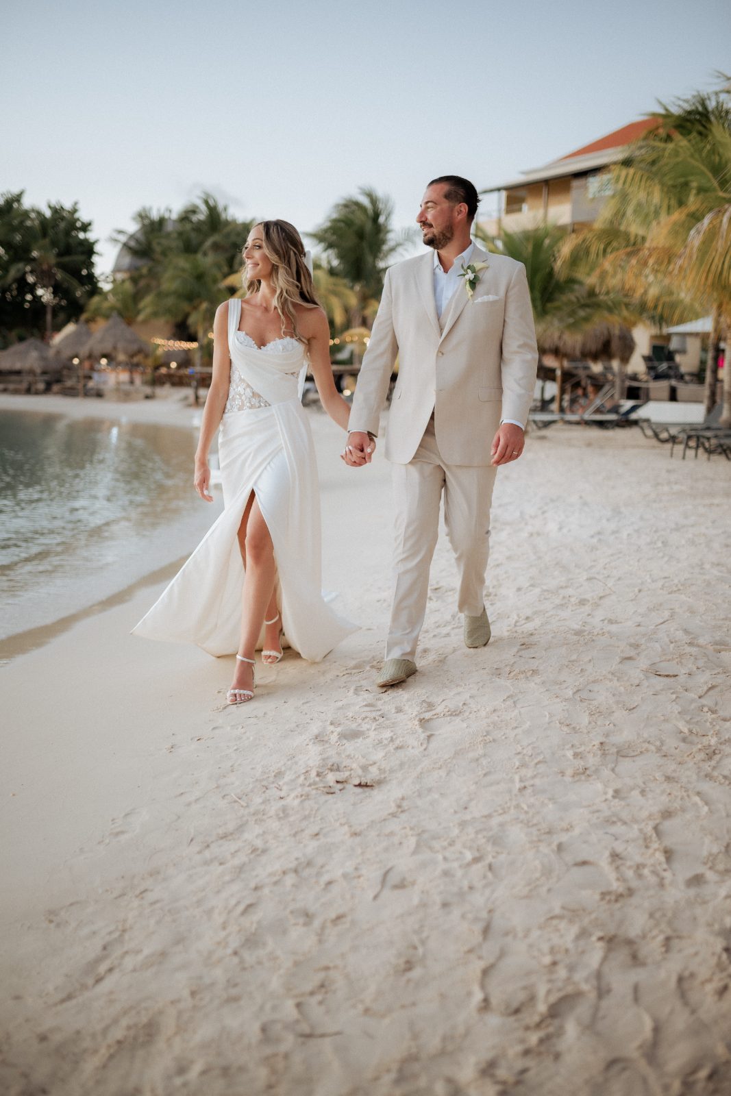 Erica and Derek walk hand-in-hand along the sandy beach at Avila Beach Hotel in Curaçao