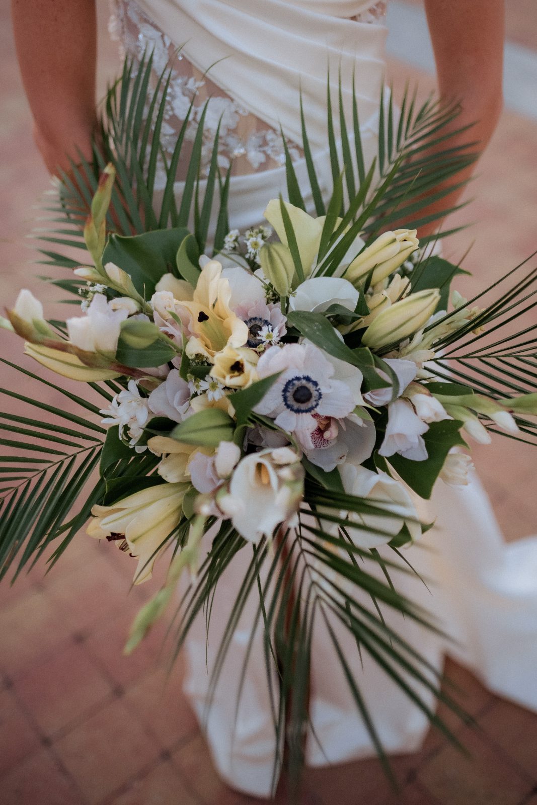 Erica holds a bouquet of white and yellow flowers while wearing a wedding dress at the Avila Beach Hotel in Curaçao