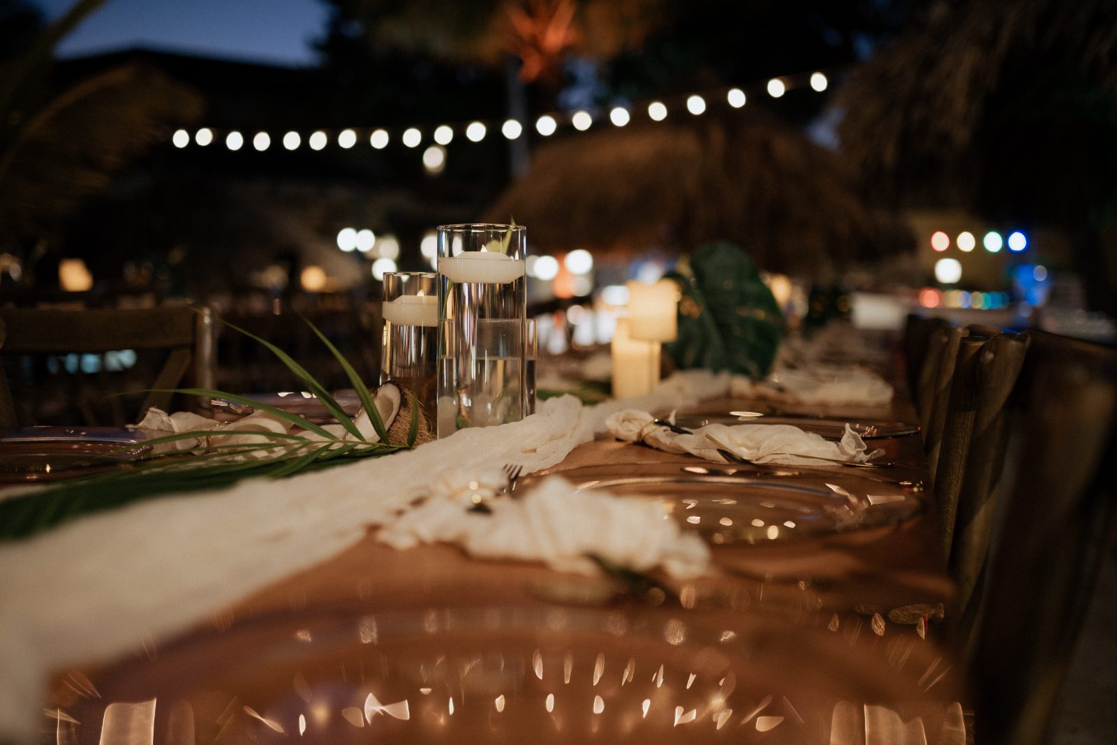 Erica and Derek's wedding table is set with elegant decor at Avila Beach Hotel in Curaçao, featuring lit candles and tropical greenery