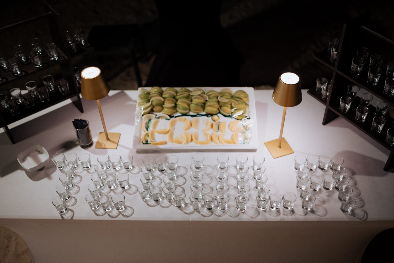 The wedding reception at Avila Beach Hotel features a dessert table with cookies and a display of shot glasses spelling "ERIKA."