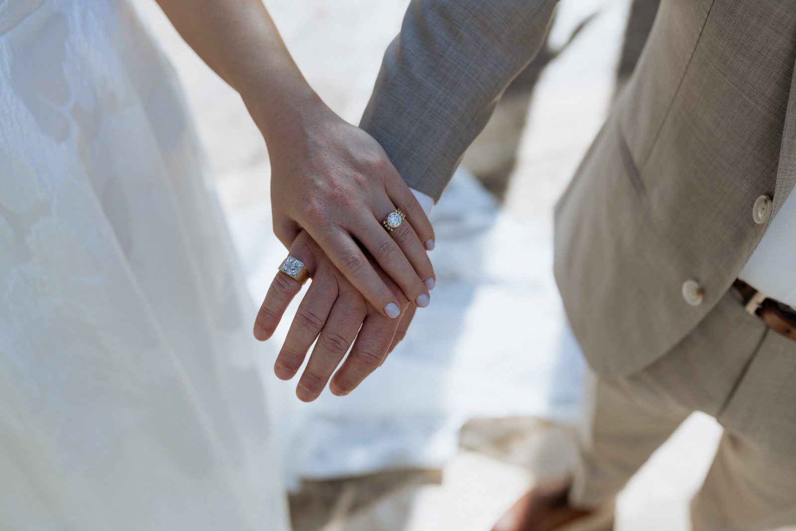 Frannie and Dustin hold hands, showcasing their wedding rings, at the Curaçao Marriott Beach Resort