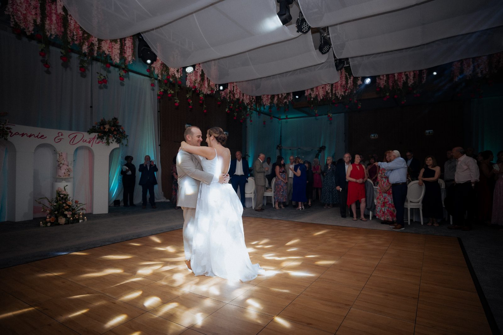 Frannie and Dustin during their first dance at their wedding reception inside the Curaçao Marriott Beach Resort, surrounded by guests and floral decorations