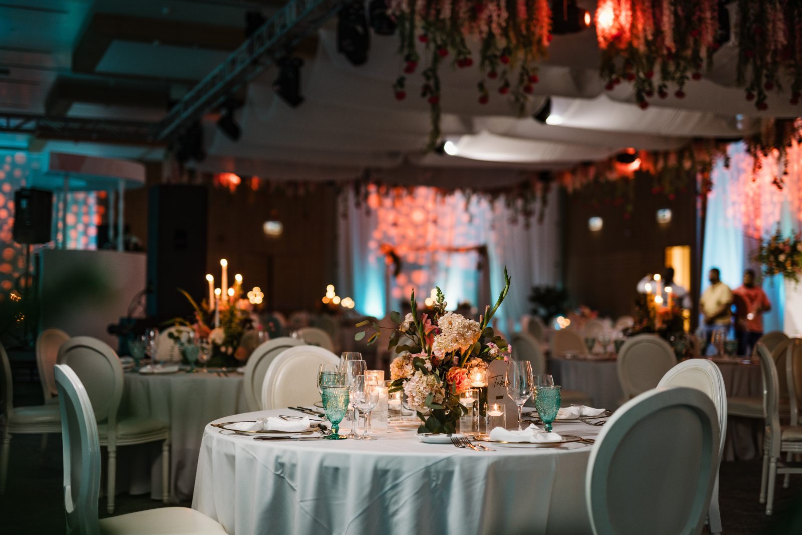 Frannie and Dustin's wedding reception at the Curaçao Marriott Beach Resort features decorated tables with candles and floral arrangements beneath softly lit drapery
