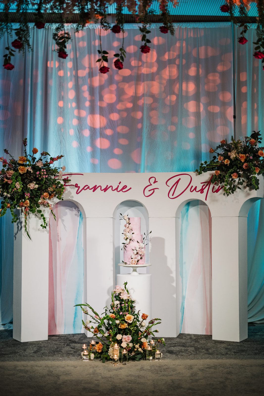 Frannie and Dustin's cake area is decorated with flowers and candles at the Curaçao Marriott Beach Resort, featuring their names prominently displayed