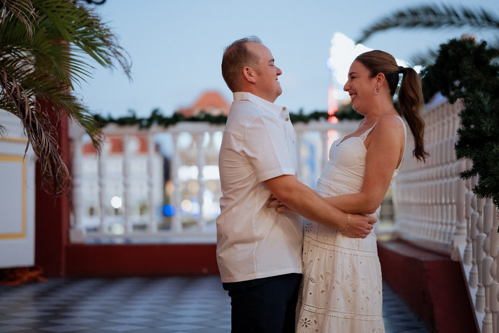 Frannie and Dustin stand together, smiling at each other on a patio decorated with greenery, at Grand Café ‘Gouverneur de Rouville’