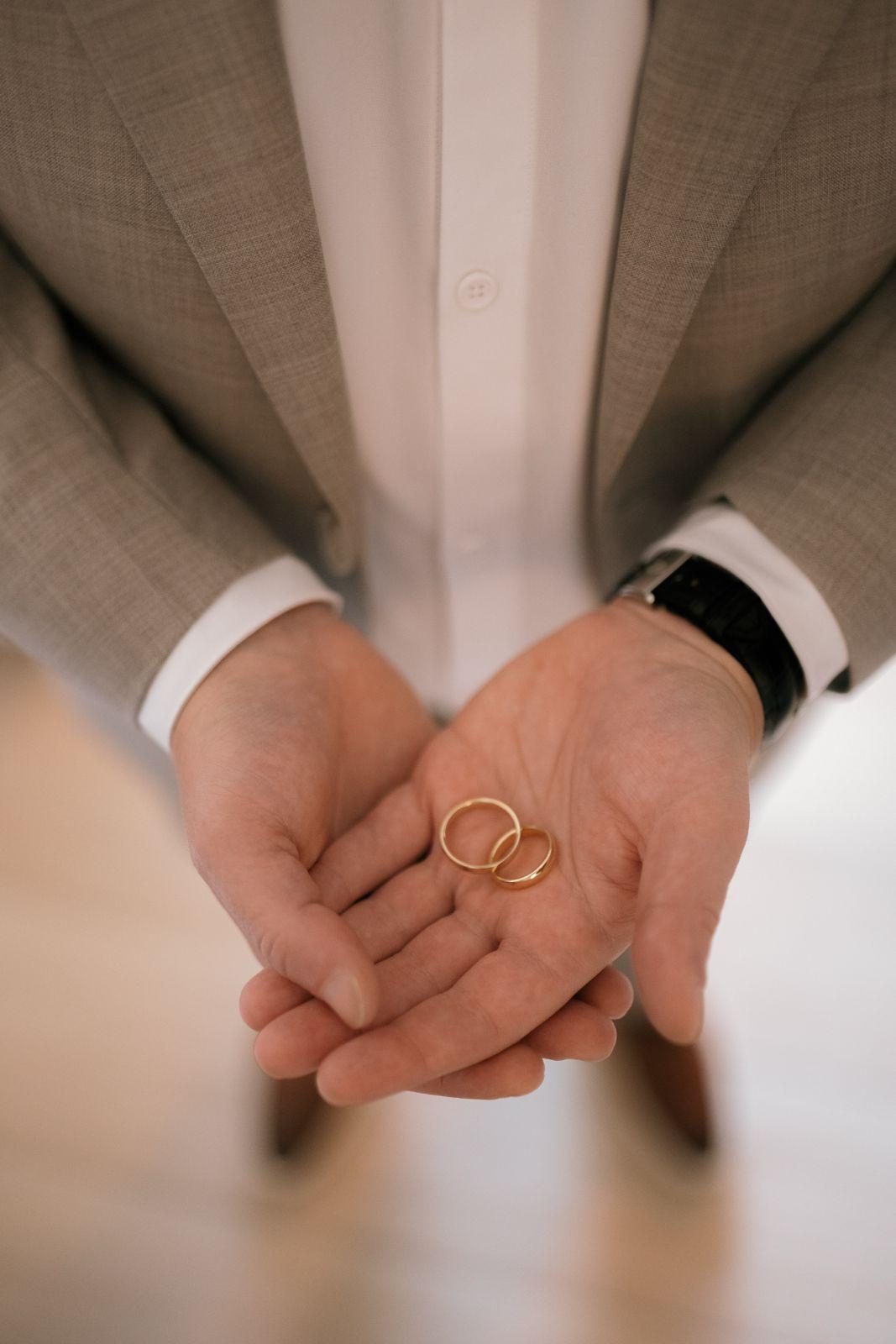 Frannie and Dustin hold wedding rings in their hands at the Curaçao Marriott Beach Resort during their wedding prep