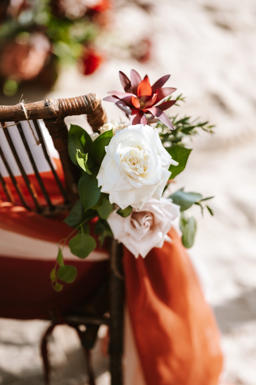 Gaëlle and Jeroen's wedding features a decorated chair with flowers at Avila Beach Hotel in Curaçao, set against a sandy background
