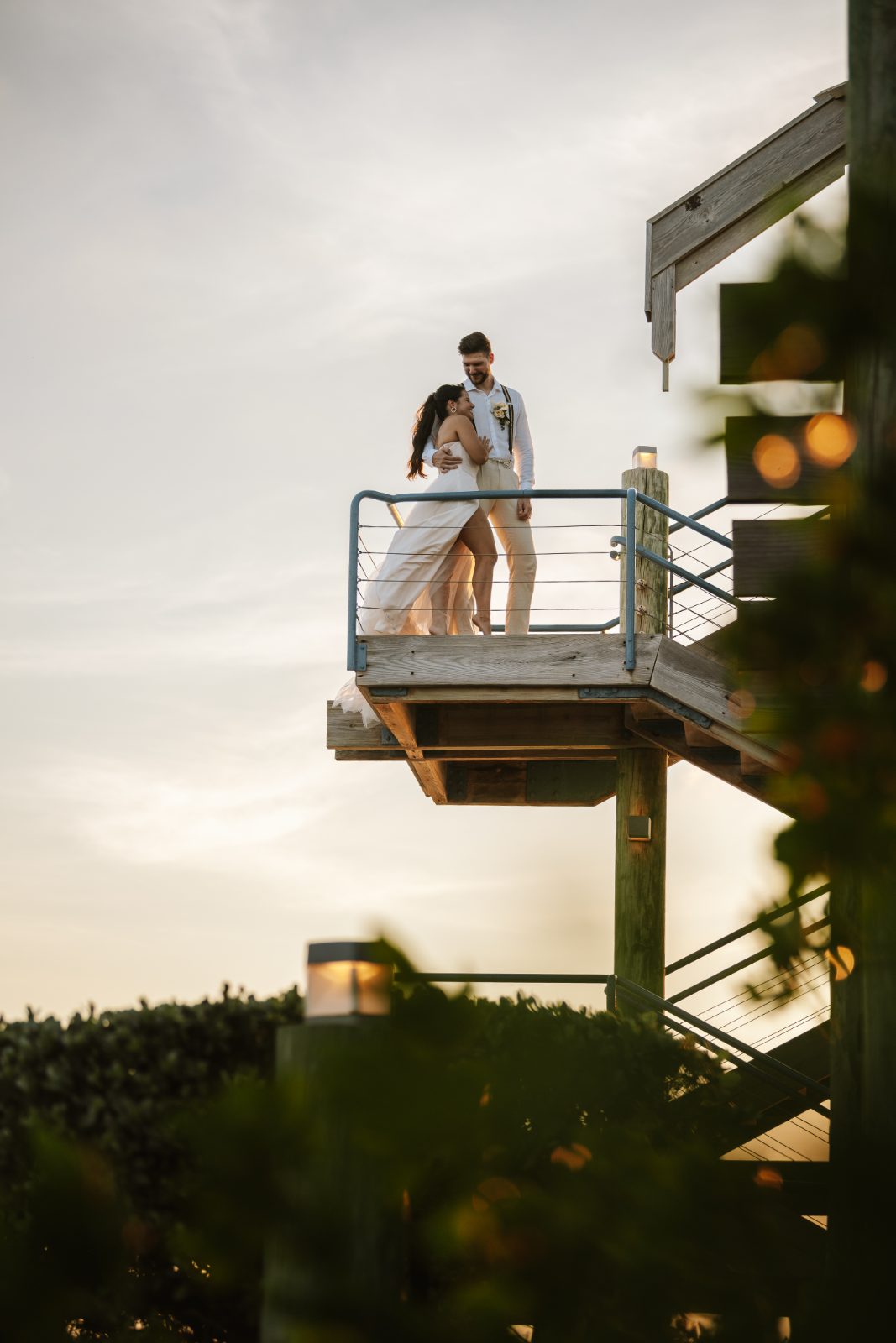 Gaëlle and Jeroen stand together on a balcony at Avila Beach Hotel in Curaçao during their wedding ceremony, with a sunset backdrop
