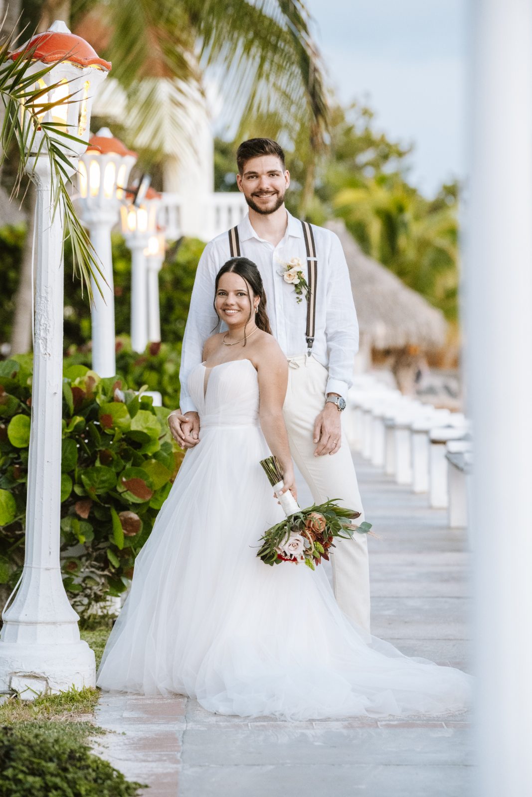 Gaëlle and Jeroen stand together on a walkway at Avila Beach Hotel in Curaçao, surrounded by greenery and palm trees