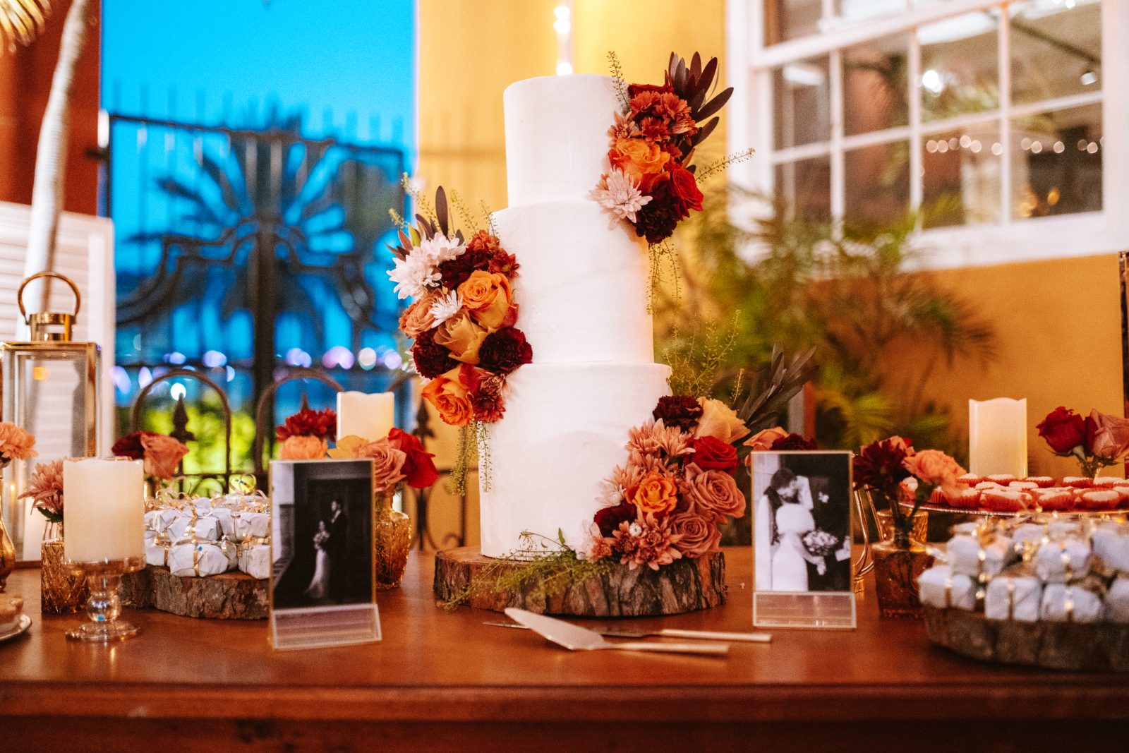Gaëlle and Jeroen's wedding cake is surrounded by floral arrangements and photographs on a table at the Avila Beach Hotel in Curaçao