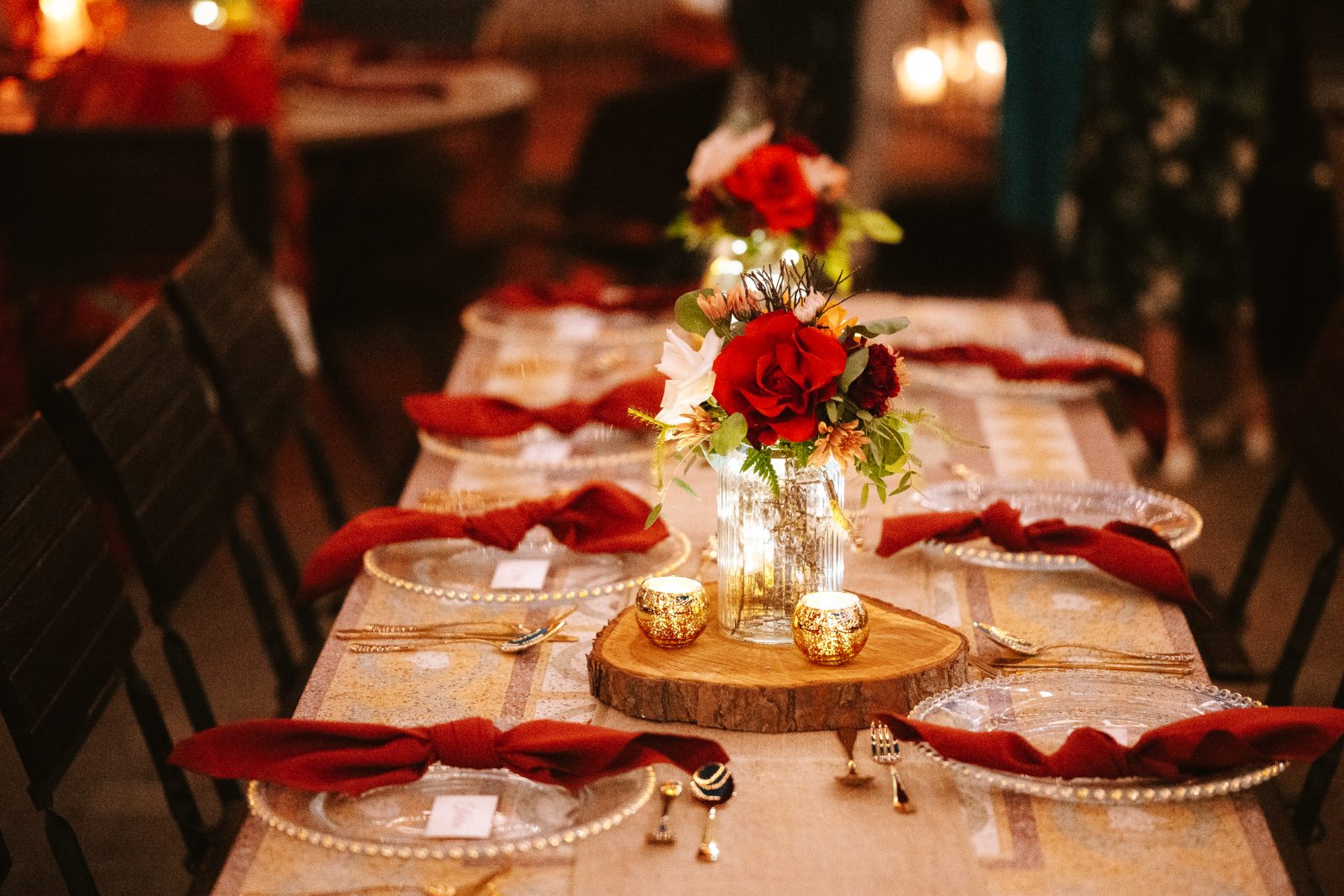 Gaëlle and Jeroen's wedding table is elegantly arranged with red flowers, candles, and dinnerware at Avila Beach Hotel in Curaçao