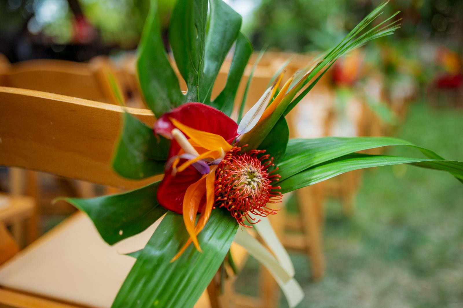 Ghislaine and Kevin are getting married in a private garden in Curaçao, with floral decorations on wooden chairs in the setting
