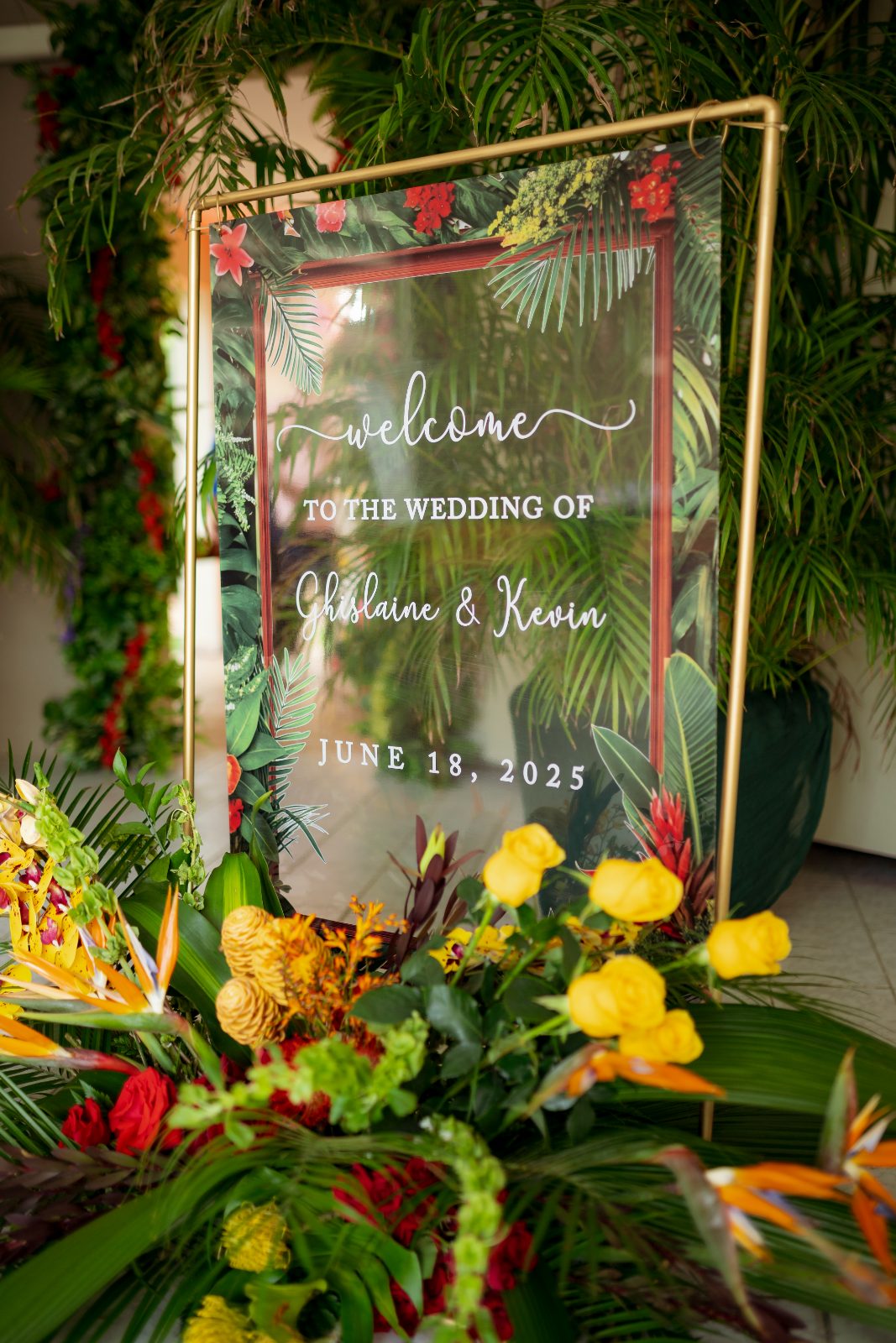 Ghislaine and Kevin's wedding welcome sign is displayed in a private garden in Curaçao, surrounded by vibrant tropical flowers and greenery
