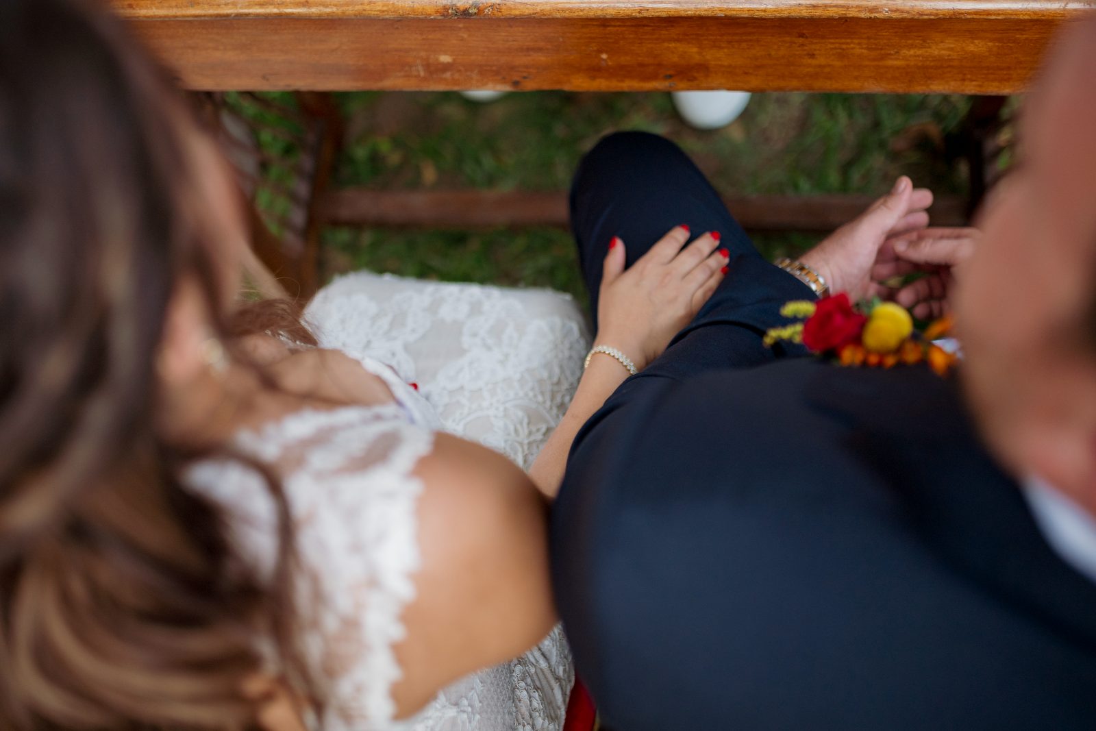 Ghislaine and Kevin are seated at a wooden table in a private garden in Curaçao during their wedding ceremony