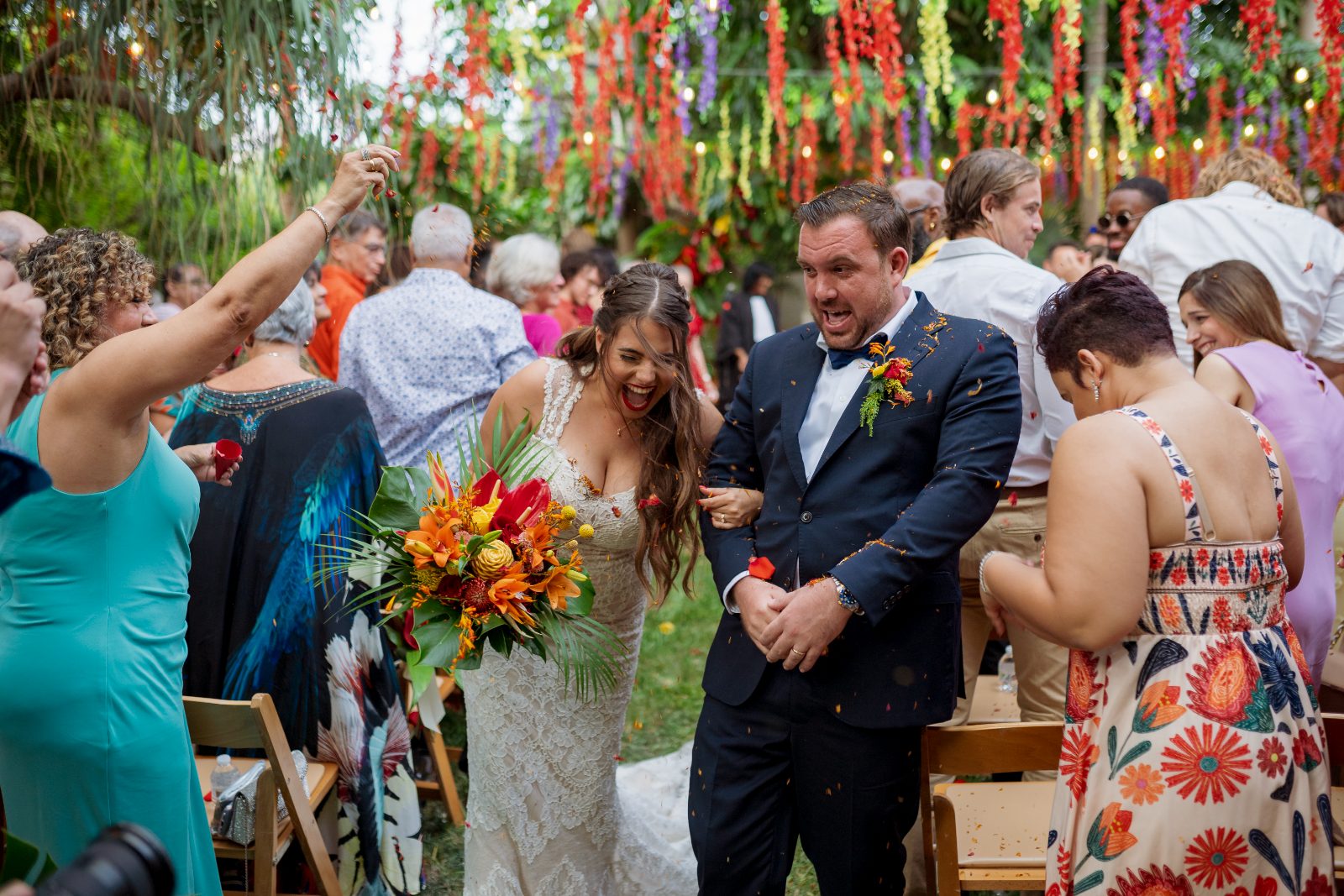 Ghislaine and Kevin celebrate their wedding in a private garden in Curaçao, surrounded by guests tossing confetti and holding floral arrangements