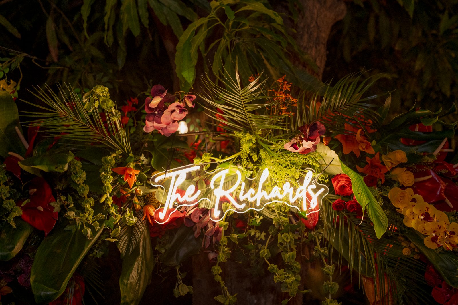 Ghislaine and Kevin's wedding is set in a private garden in Curaçao, featuring a decorative sign that reads "The Richards" surrounded by tropical flowers