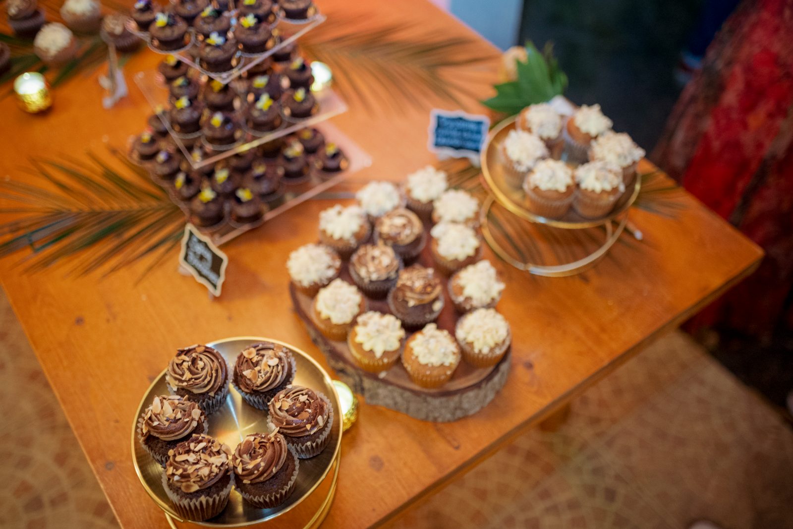 Ghislaine and Kevin's wedding reception features a table with various cupcakes amid a private garden setting in Curaçao