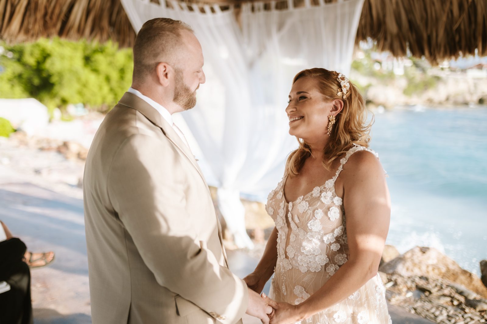 Jennifer and Weston are exchanging vows under a thatched roof at Karakter, Curaçao, with the ocean in the background
