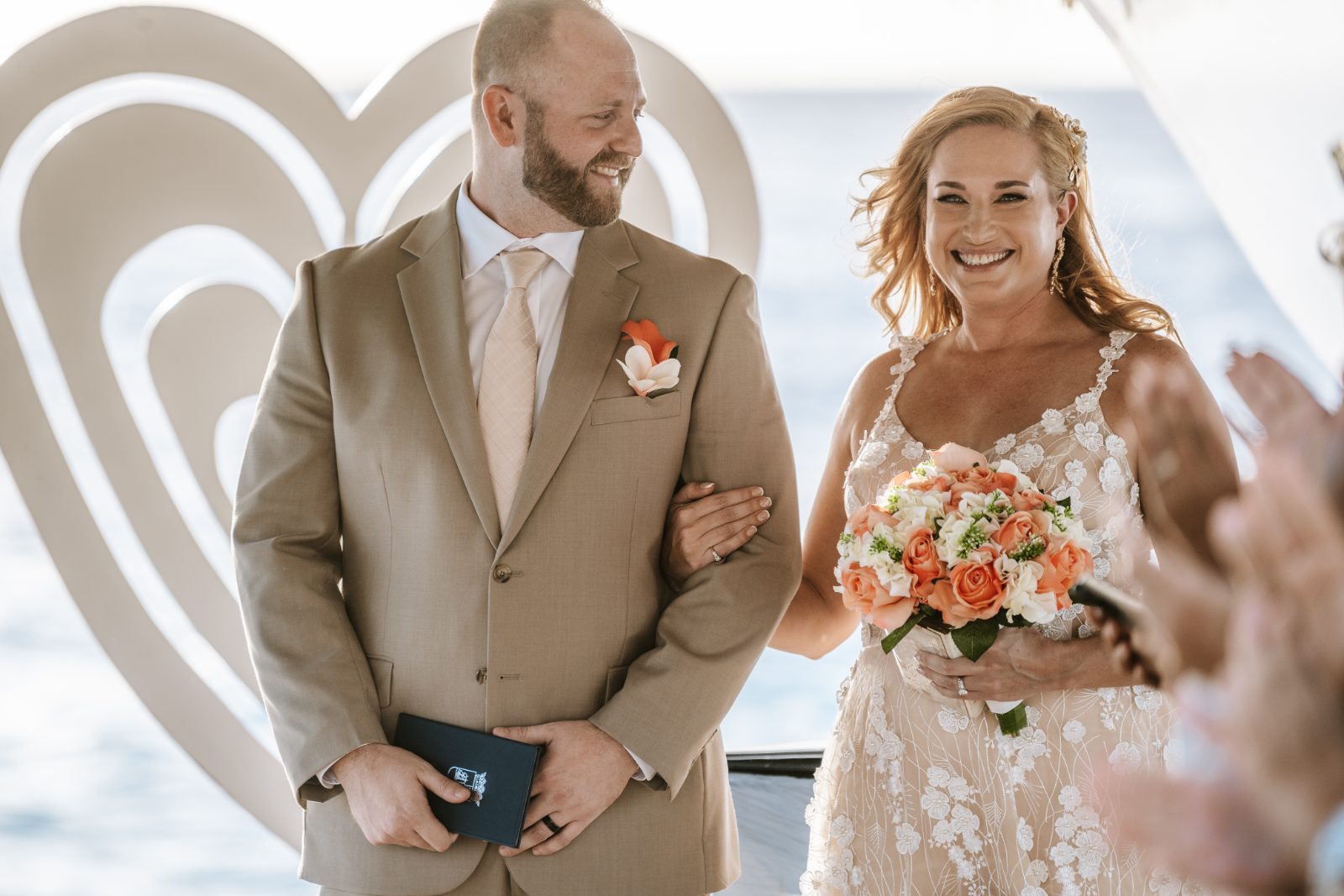 Jennifer and Weston stand together at their wedding ceremony at Karakter, Curaçao, with Jennifer holding a bouquet and smiling
