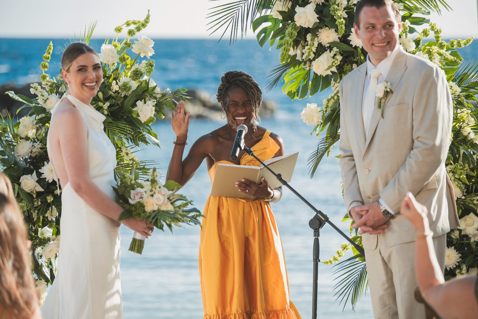 Jessica and Bogdan stand at the altar during their wedding ceremony at Avila Beach Hotel in Curaçao, facing an officiant and guests