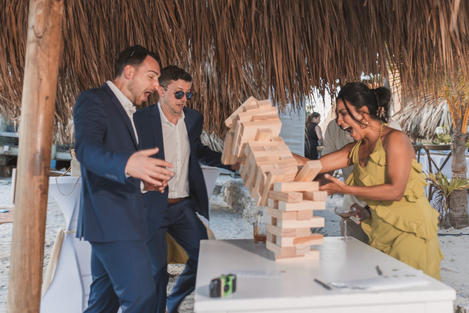 Jessica and Bogdan's wedding at Avila Beach Hotel features guests playing Jenga under a thatched roof on the beach
