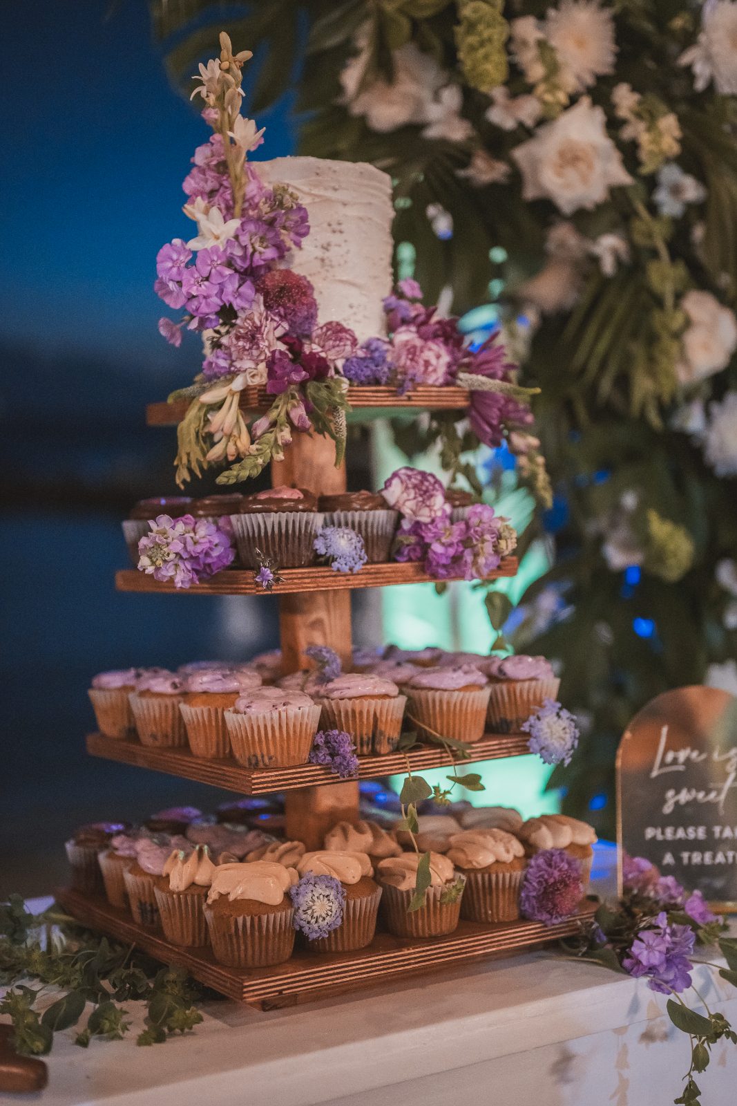 A tiered cupcake display decorated with flowers is set up at a wedding reception at Avila Beach Hotel in Curaçao