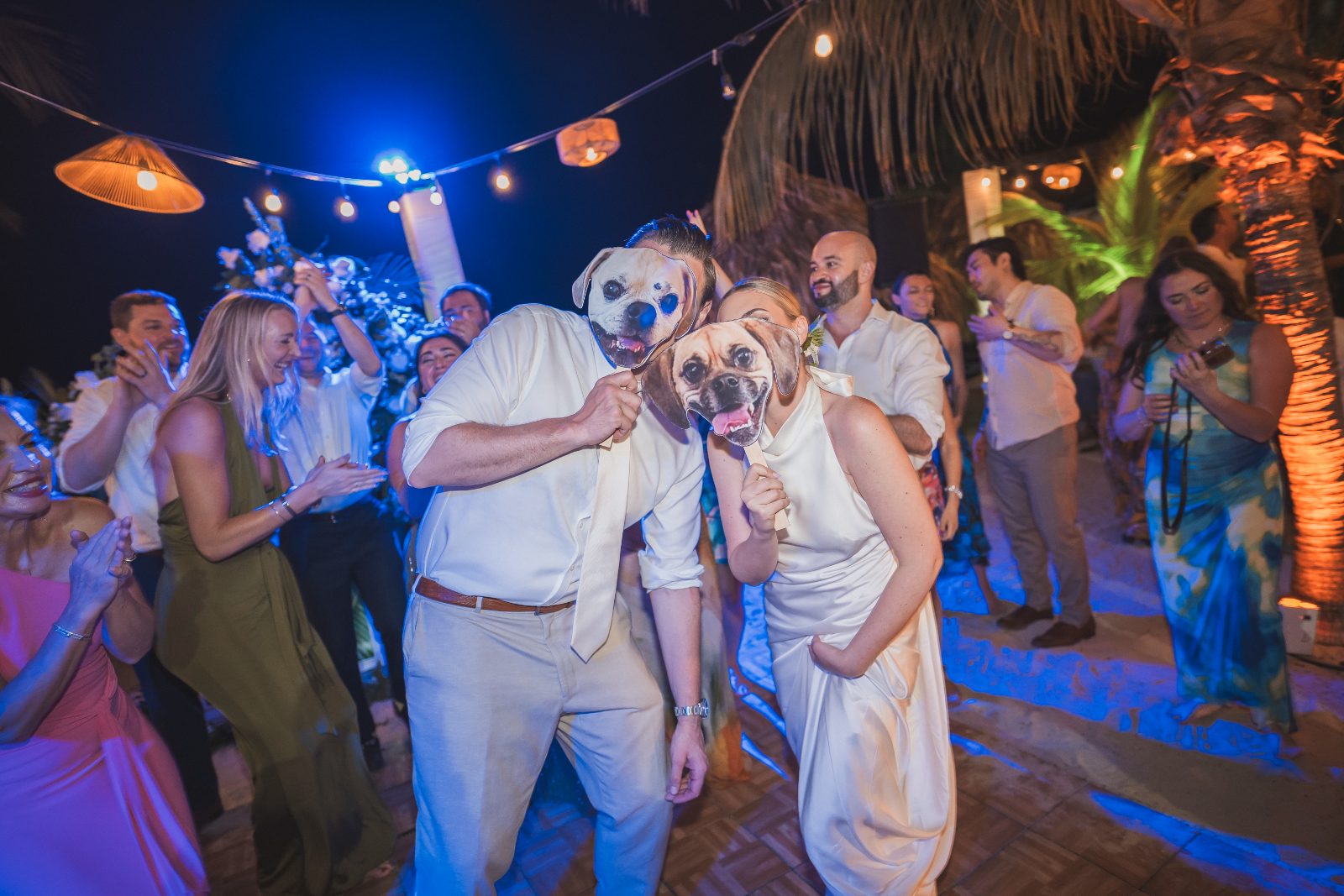 Jessica and Bogdan celebrate their wedding at Avila Beach Hotel in Curaçao, wearing dog masks and surrounded by guests on a vibrant dance floor