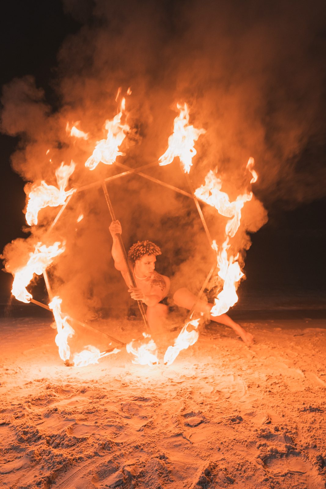 A fire performer twirls flaming poi in a display on the beach at Avila Beach Hotel in Curaçao during Jessica and Bogdan's wedding celebration