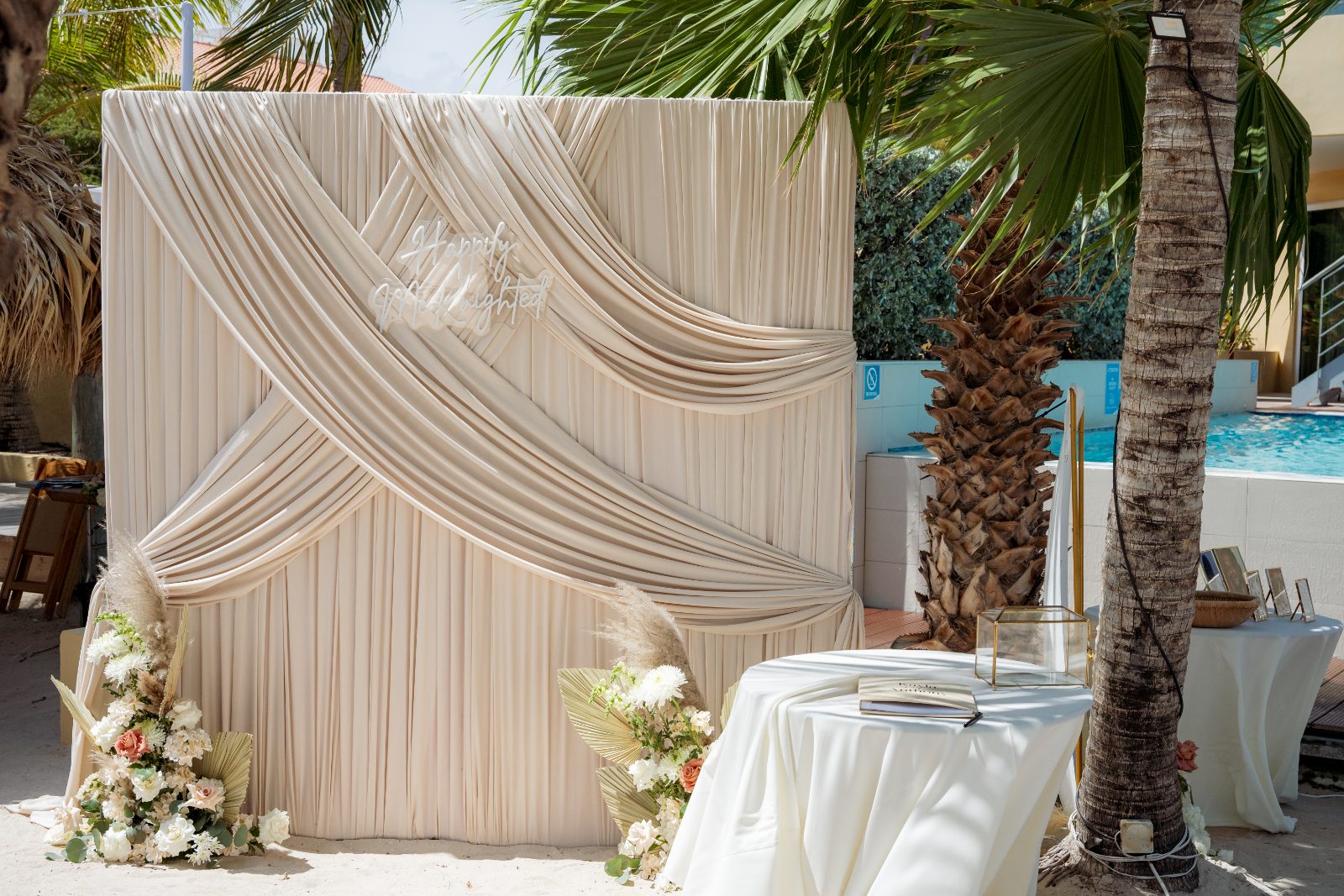 Kayla and Anthony's wedding ceremony is set at Avila Beach Hotel, featuring a decorated backdrop with floral arrangements and a signing table