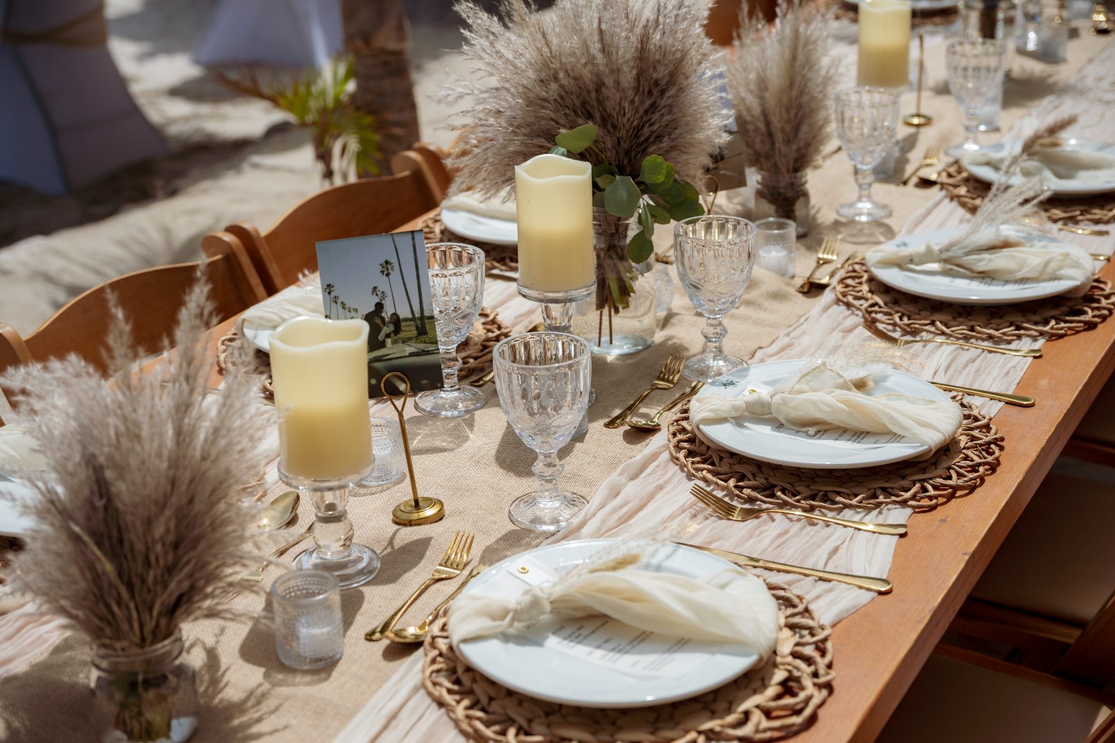 Kayla and Anthony's wedding reception table at Avila Beach Hotel features elegantly set plates, glasses, and decorative elements