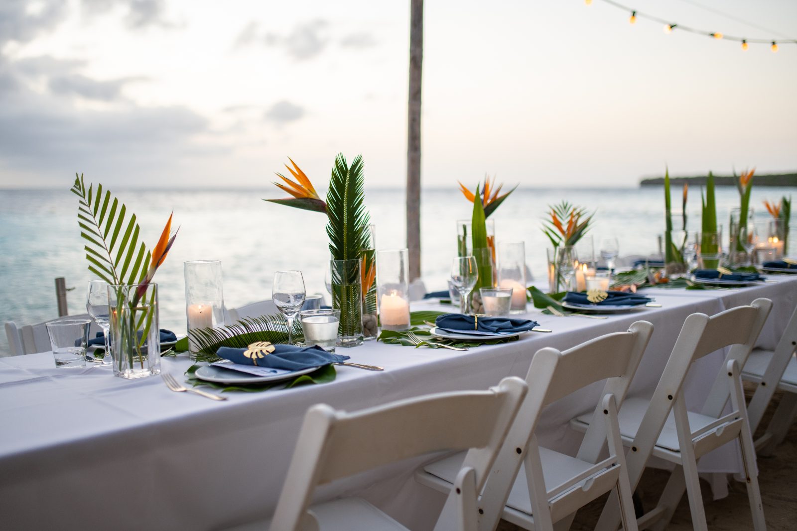Kinga and Sven's wedding reception features a beautifully arranged dinner table with candles and tropical decorations along the waterfront at Karakter, Curaçao